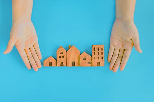 Hands framing a row of small wooden model buildings